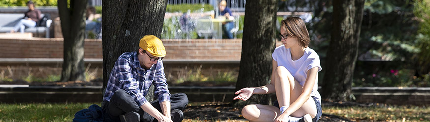 photo of two students sitting outside on campus