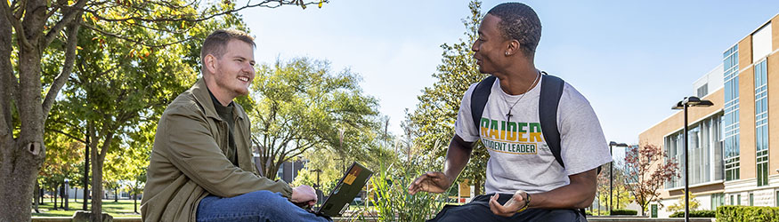 photo of two students sitting outside on campus