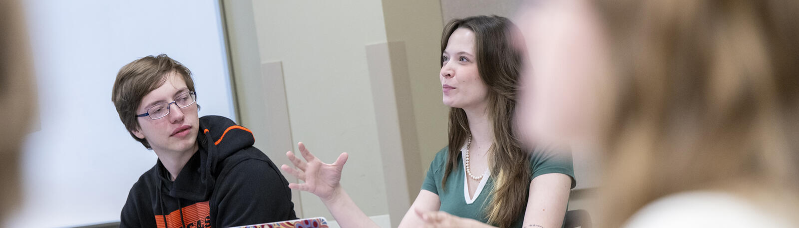 a student speaking in a classroom discussion while other students listen