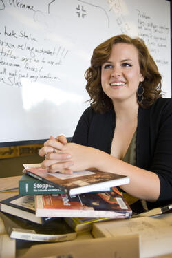 photo of a student sitting at table with a stack of books